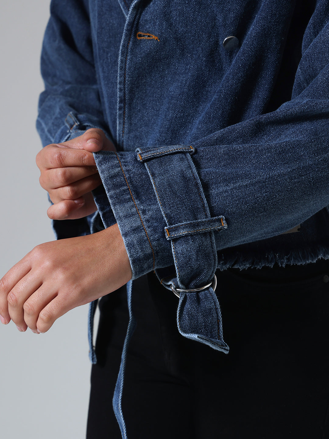 Close-up of a person wearing a blue denim jacket with a plain background