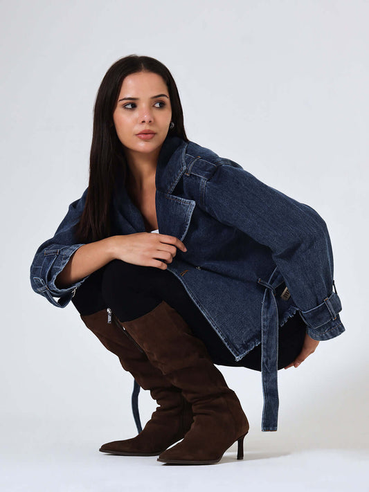 Woman wearing a denim jacket and brown boots on a white background